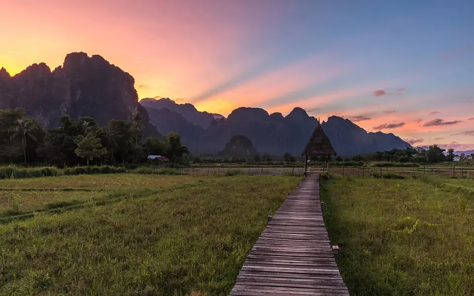 A walkway to a riverside hut at sunset near Vang Vieng
